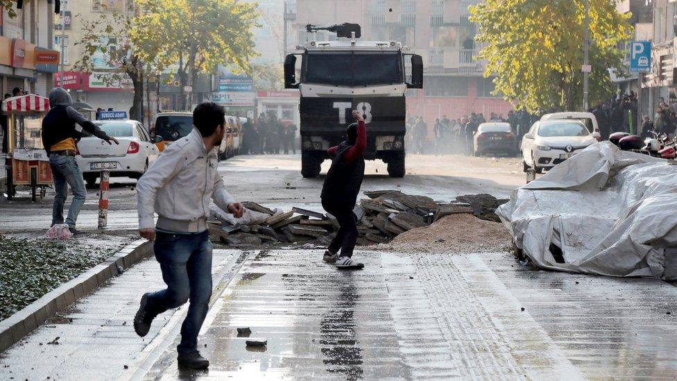 A demonstrator throws stones at a police vehicle during a protest against the curfew in Sur district, in the southeastern city of Diyarbakir, Turkey (18 December 2015)