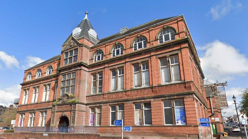 A street-view image of the front of the Tunstall Library and Baths - a three-storey red brick Victorian building 