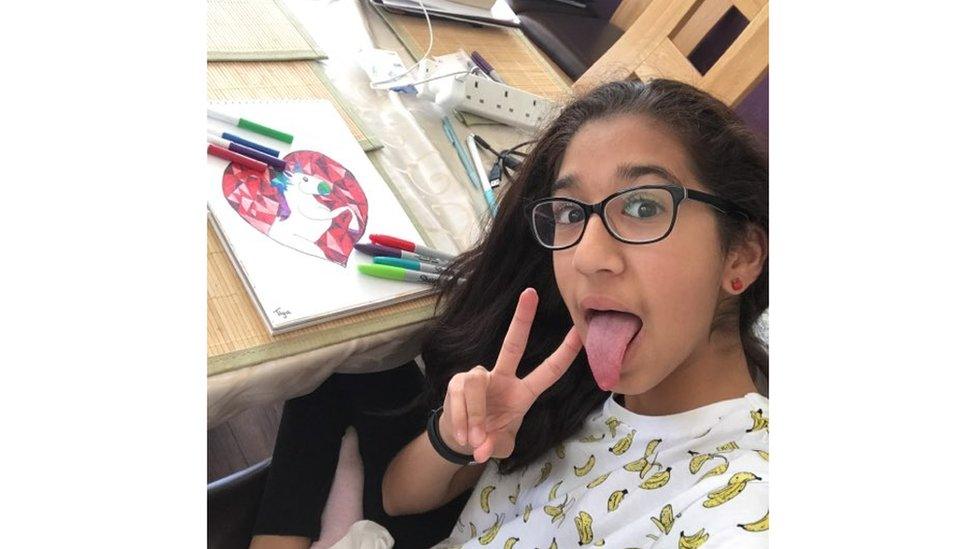 Girl poses for selfie with tongue out next to a drawing of a unicorn in a heart.