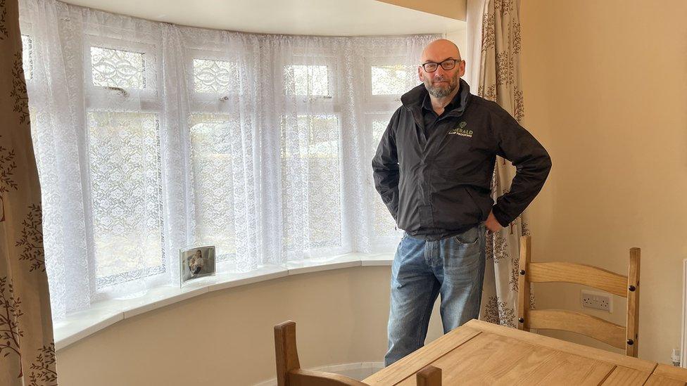 Brendan O'Neill in a branded jacket standing by a window in the cleaned home