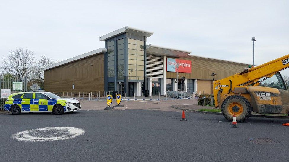 Essex Police car in front of Home Bargains and a JCB telehandler