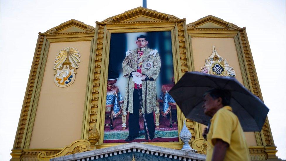 A man walks past a portrait of Thailand's King Maha Vajiralongkorn near the Grand Palace in Bangkok on May 3