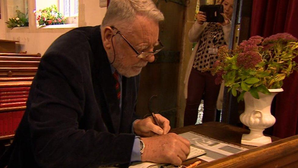 Terry Waite signing visitors book at St Michael and All Angels church