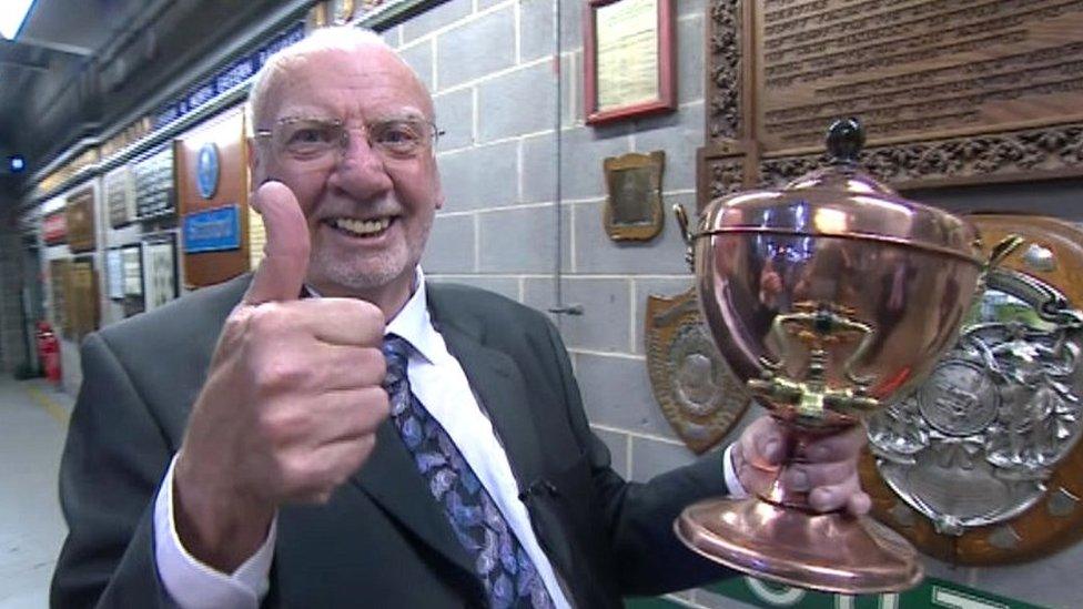 Man giving thumbs up with a trophy