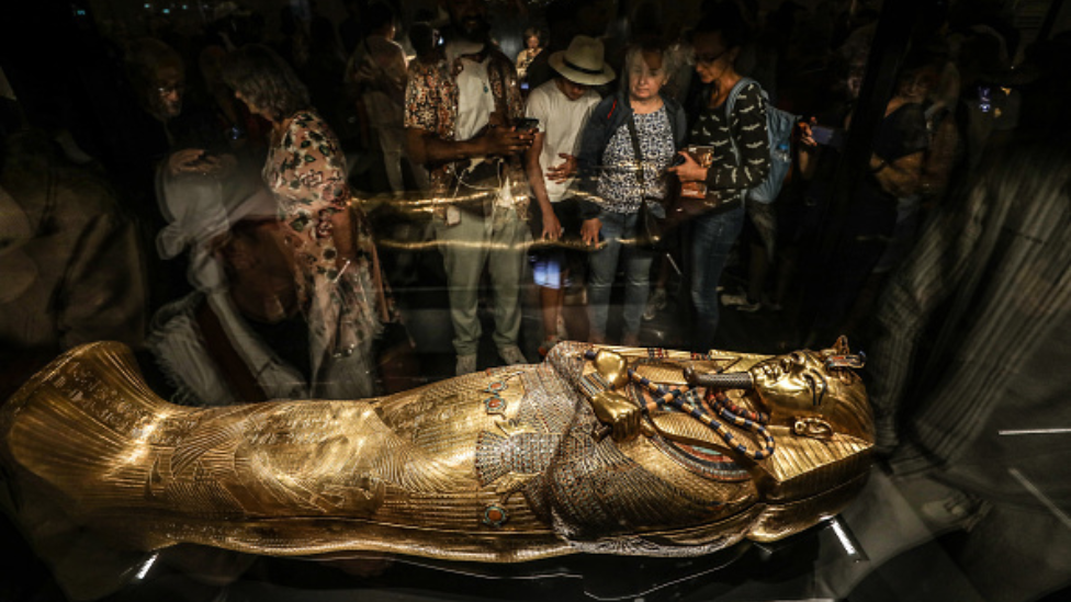 Visitors look at the golden coffin of Tutankhamun, the famous pharaoh of Ancient Egypt, on display at the Grand Egyptian Museum, which sheds light on thousands of years of Egyptian history and houses hundreds of historical artifacts near the Giza Pyramids, in Giza, Egypt on November 4, 2025.
