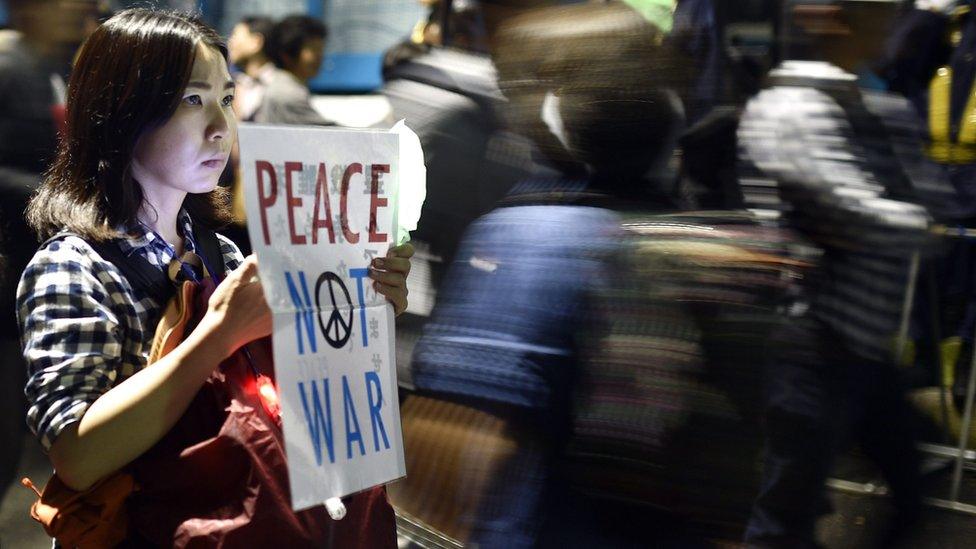 A young woman holds a placard protesting against the controversial military reform bills outside the Japanese parliament in Tokyo, Japan on 18 September 2015,