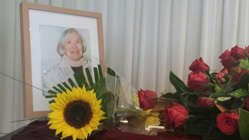 A picture of Lee's oma and flowers on top of her coffin