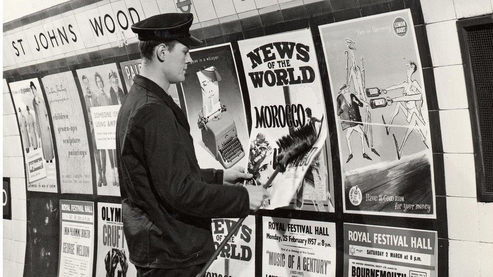 A uniformed man putting up posters in St John's wood underground station