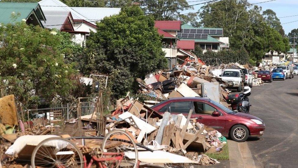 Debris is piled up next to homes in Lismore