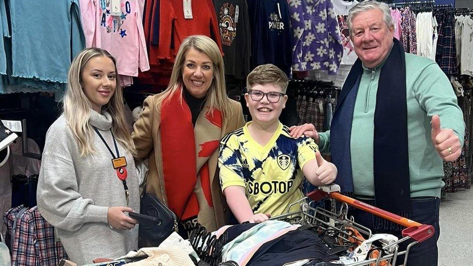 Tommy surrounded by his family in a clothes shop