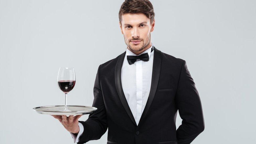 Waiter carrying glass of wine on tray