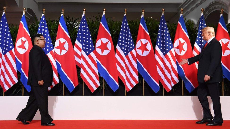 US President Donald Trump (R) and North Korea's leader Kim Jong Un (L) walk towards one another at the start of their historic US-North Korea summit, at the Capella Hotel on Sentosa island in Singapore on June 12, 2018.