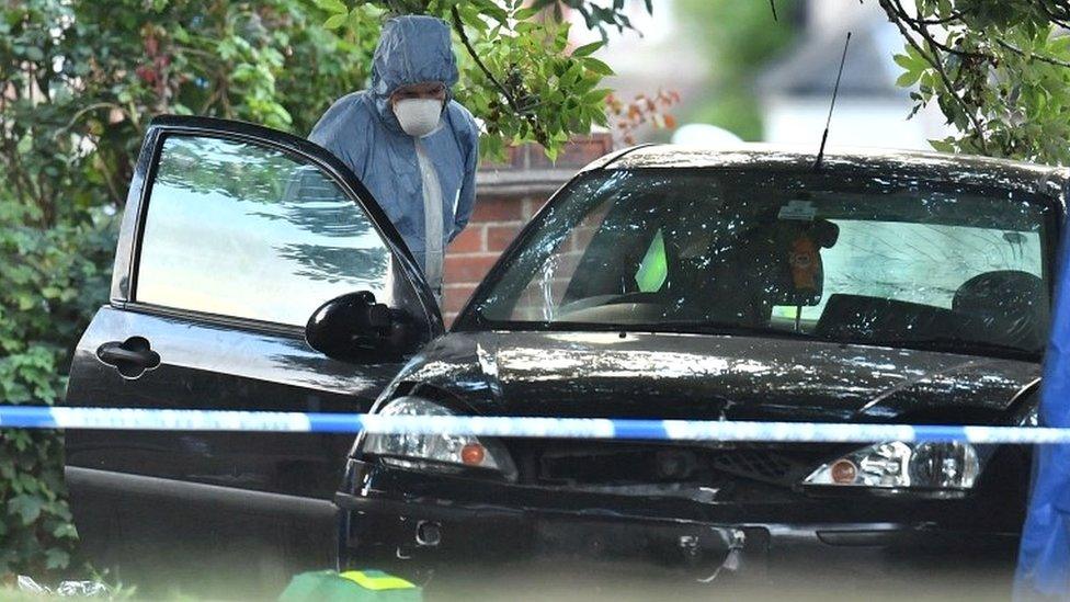 Forensic police officer examining car in Lennard Road