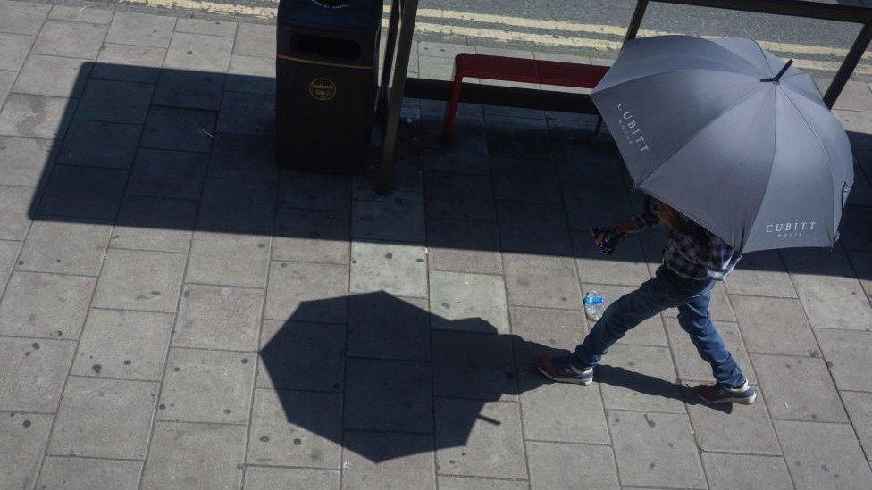 person sheltering under umbrella