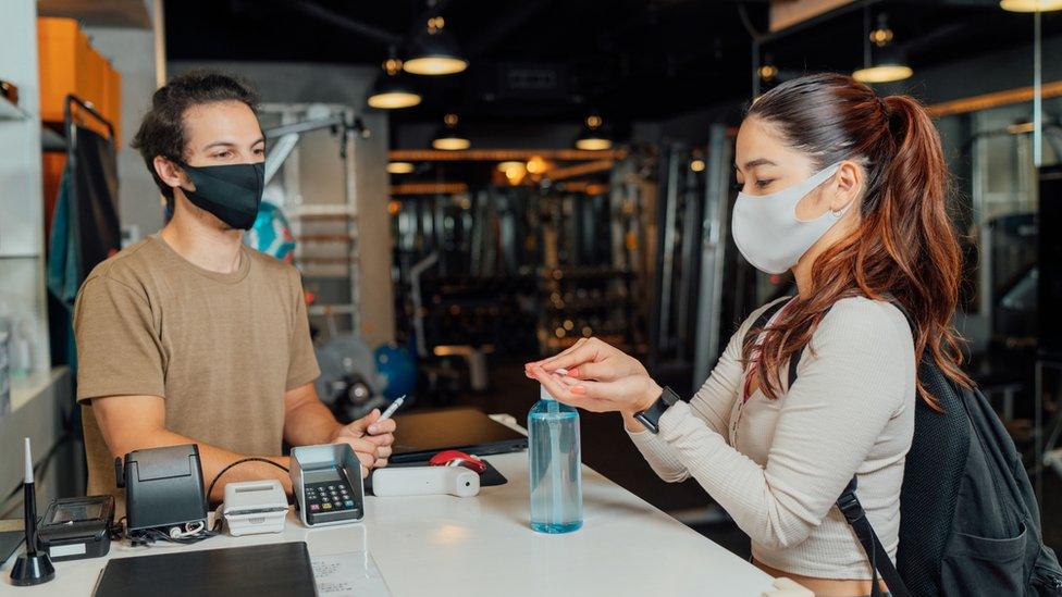 Woman applying hand sanitiser gel at entrance of gym - stock photo