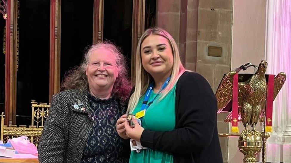 A newly qualified nurse holding a badge with a family member