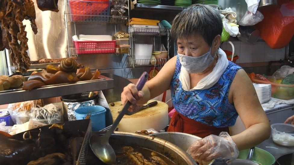 Lim Bee Hong preparing food at her small food stall in Singapore, April 21, 2020