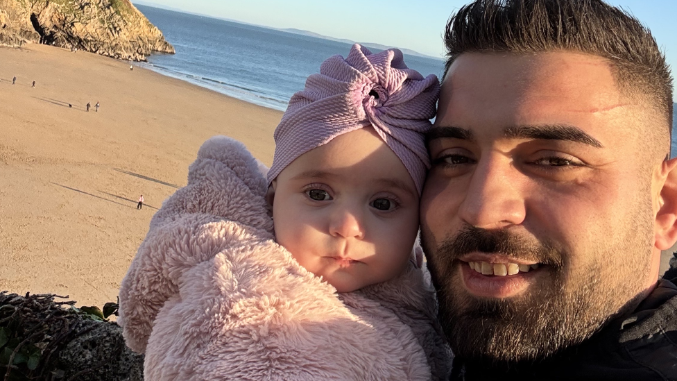 A selfie of Sophia Kelemen and her dad Alex on Tenby beach. She is wearing a fluffy pink coat and an oversized pink headscarf while he has on a black coat