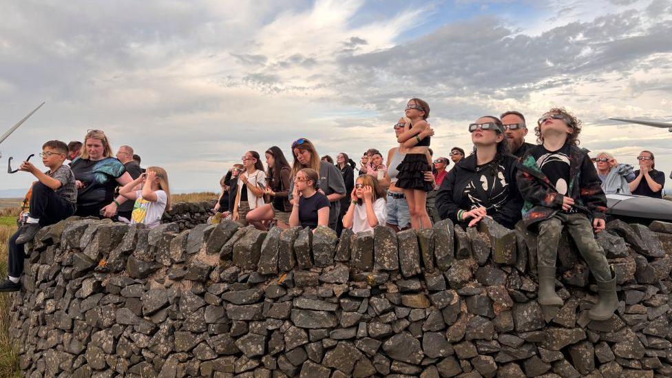 Clouds at Whitelee Wind Farm scuppered the view most of the time, but the crowd pictured here looked up when they parted to see a sliver of sun from behind the moon 