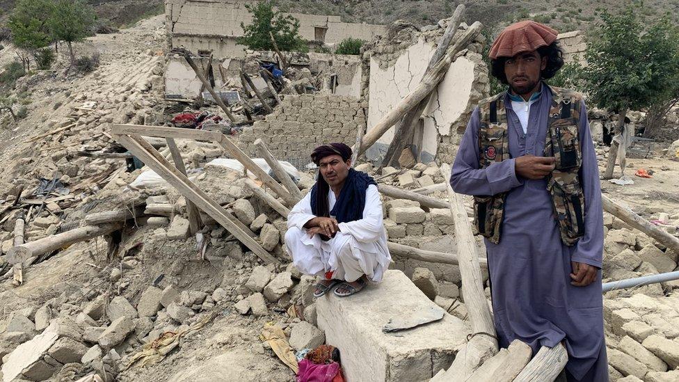 Image shows two men amid rubble