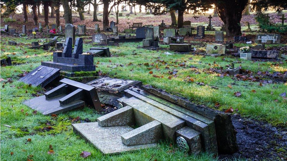 A group of headstones all pushed over