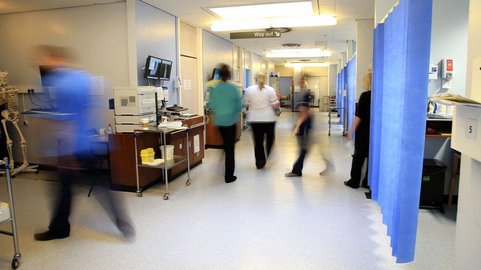 Nurses and other hospital staff walking in a hospital ward