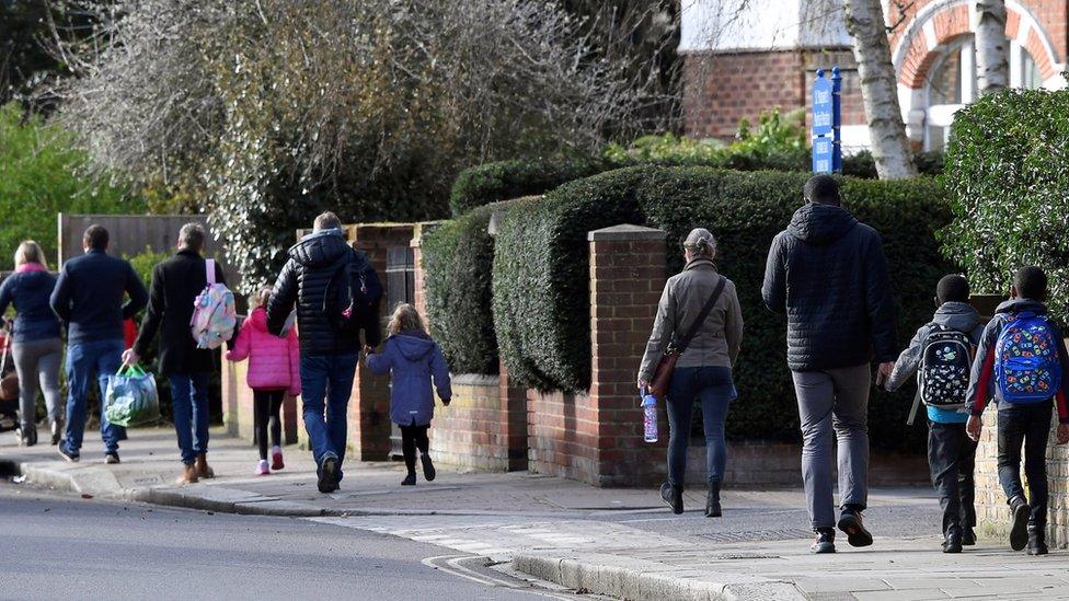 Parents walk their children to school on the last day before their official closure