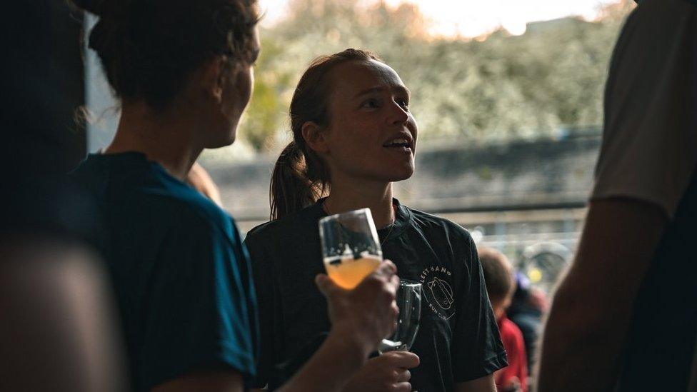 Cat Hicks in conversation with someone nearby holding a beer