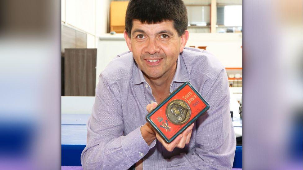 Auctioneer with tin of chocolates