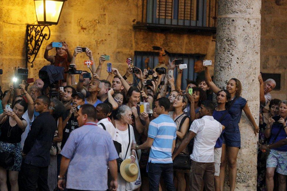 Tourists and local residents take pictures as resident Barack Obama tours Old Havana with his family at the start of a three-day visit to Cuba, in Havana