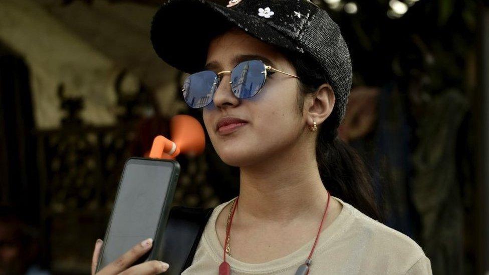 woman cools herself with phone fan