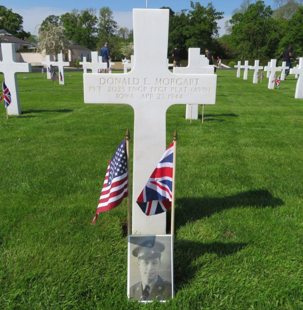 The grave of Donald Morgart, from Iowa, who died on 23 April 1944, with a British and American flag and his photo