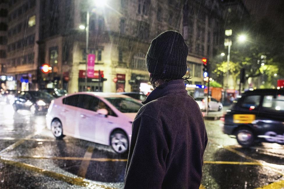 A homeless person next to a busy road