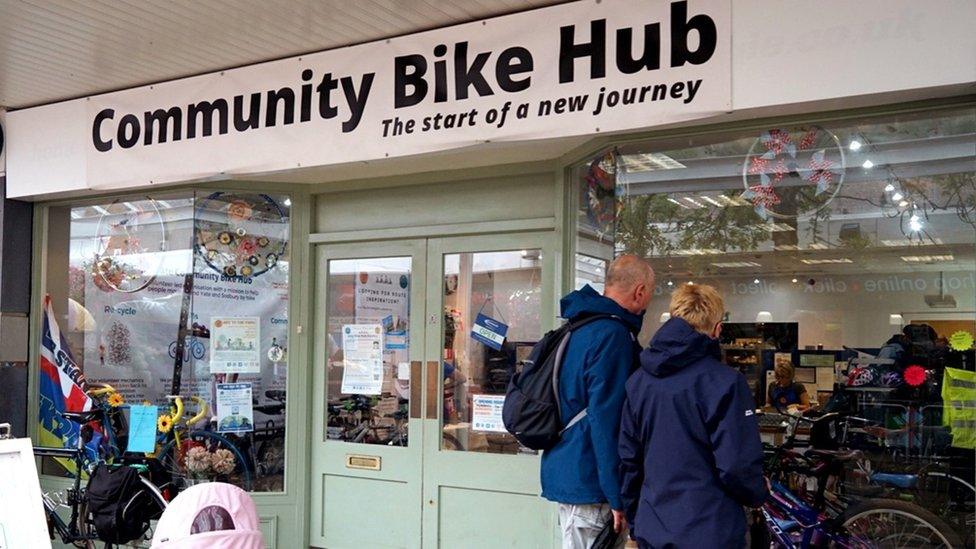 Man and woman look in window of bike shop