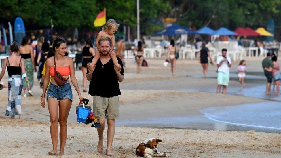 Family of three walk on Sri Lankan beach