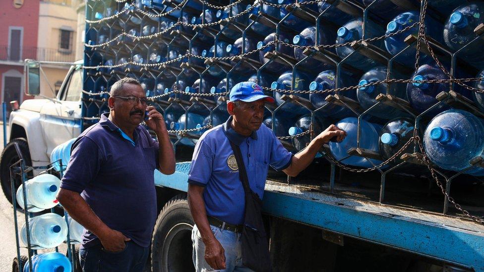 Workers deliver water bottles in Caracas on March 27, 2019 during a power outage in Venezuela