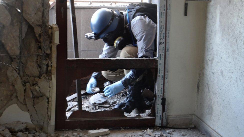 A UN expert collects samples at a site where rockets filled with Sarin hit a suburb of Damascus, Syria (29 August 2013)