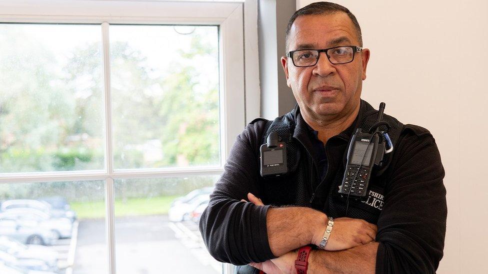 Escort Officer Hassan Segari wearing glasses and police uniform looking into the camera