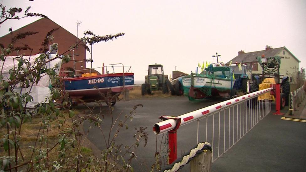 Cullercoats boatyard is a small area with a house on either side and about 3 boats visible wit a number of tractors there too 