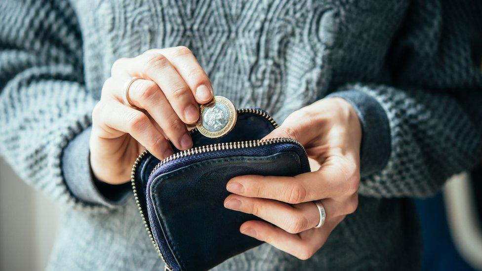 Money in a hand being placed in a purse