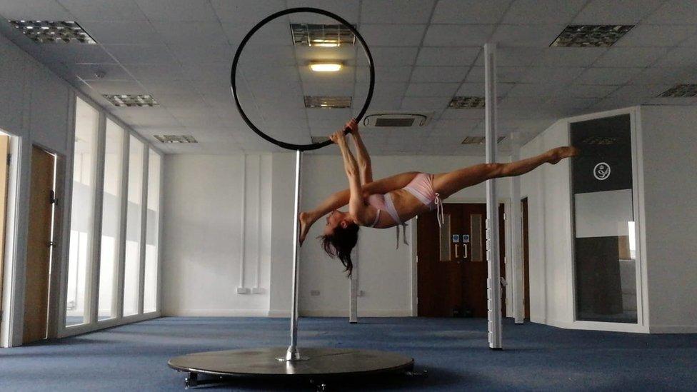 Woman hanging upside down from a pole