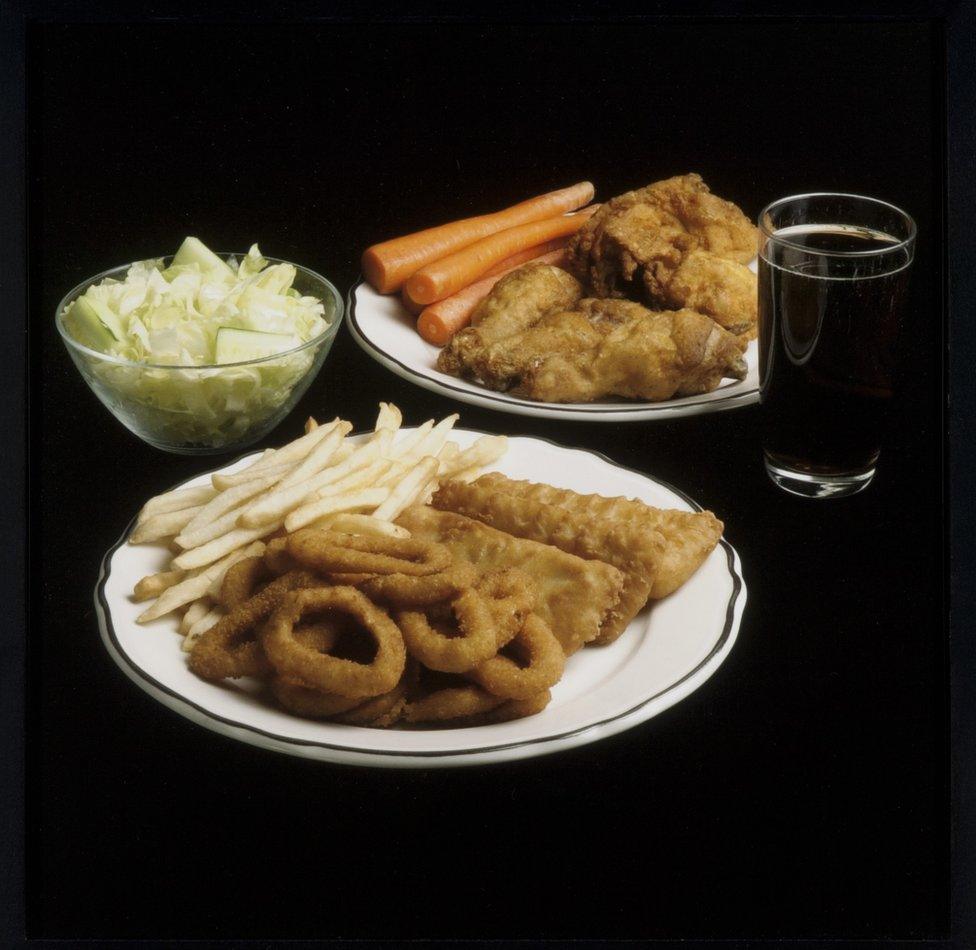 A meal featuring lettuce, onion rings, french fried, carrots and chicken nuggets