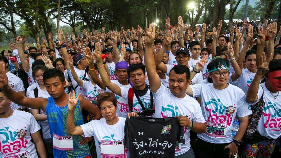 Runners flash three finger salute as they attend at "Run Against Dictatorship" event at a public park in Bangkok