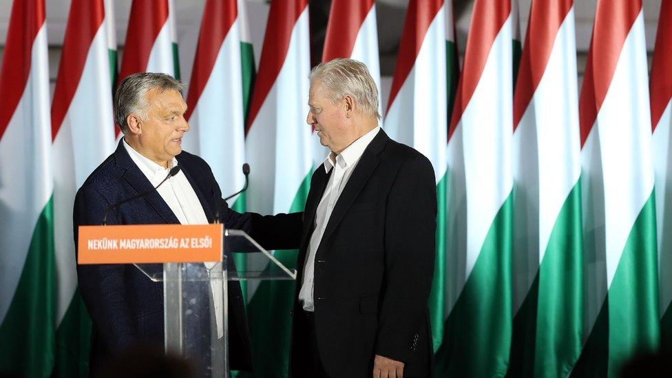 The two politicians stand at a podium with Hungary flags in the background