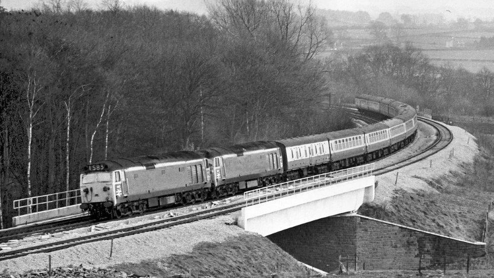 A train crosses a bridge over the A66