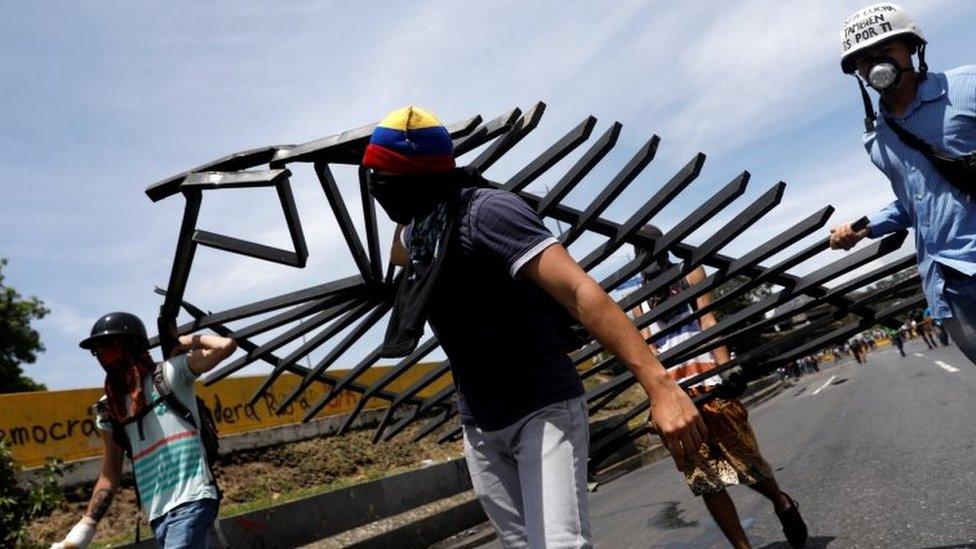 Opposition activists carry materials to build a barricade on a street in Caracas. Photo: 15 May 2017