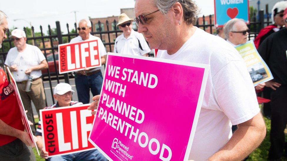 A supporter of Planned Parenthood walks past anti-abortion demonstrators in Missouri in May 2019