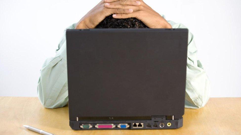 Man hiding behind laptop