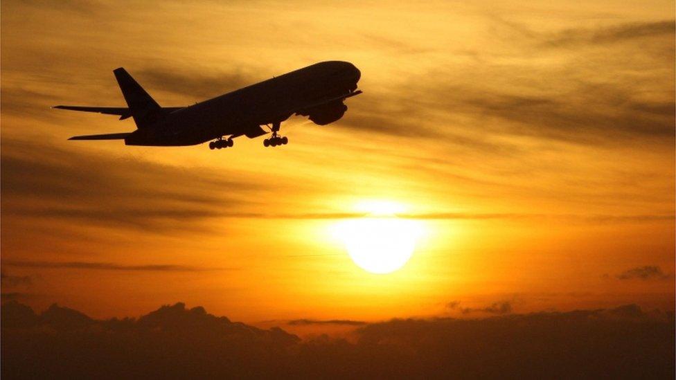 A plane flying infront of a sunset