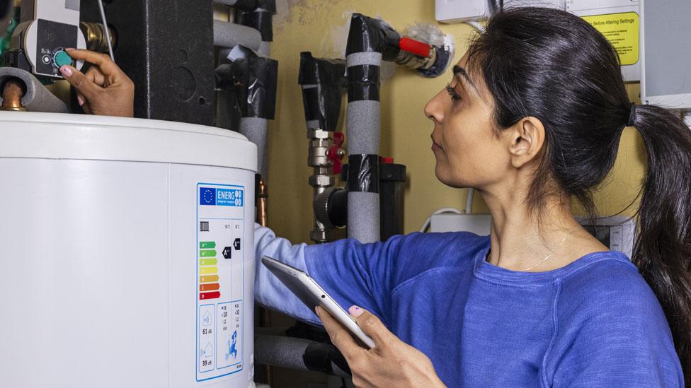 A woman adjusts her thermostat at home